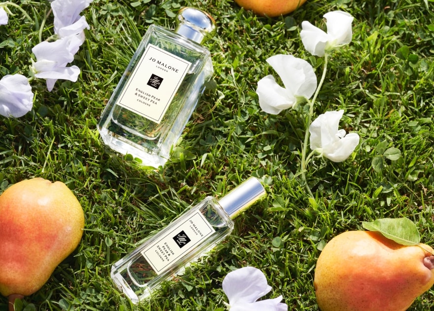 English Pear and Freesia colognes and candle on a table with a pear