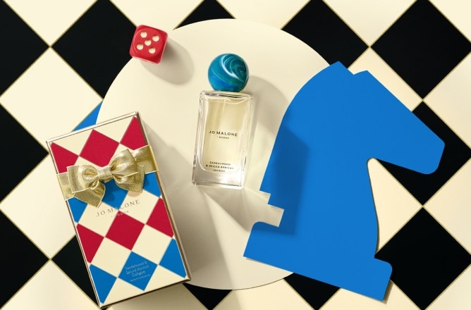 Launch image of advent calendar dartboard box shown open with examples of 5 product contents on checkerboard background.