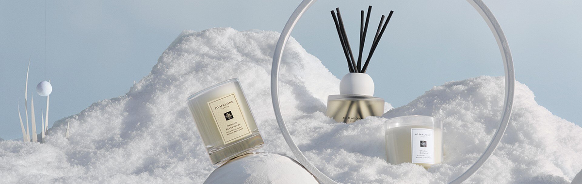 snowy background with travel candles, diffusers and miniature votive candles